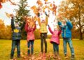Herbstlaub bedeckt eine europäische Familie, die in einer Herbstlandschaft spielt