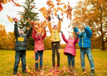 Fall foliage covering European family playing in autumn landscape