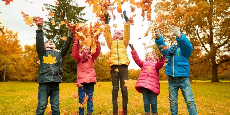 Fall foliage covering European family playing in autumn landscape