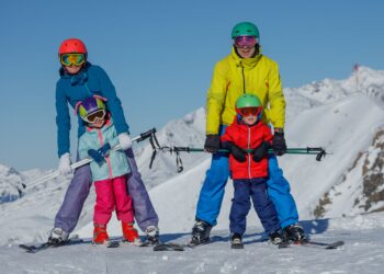 Skiers family enjoying early snow season conditions at European Alps resort destination
