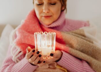 Woman enjoying winter wellness with candles in Danish hygge style interior featuring warm lighting and cozy textiles
