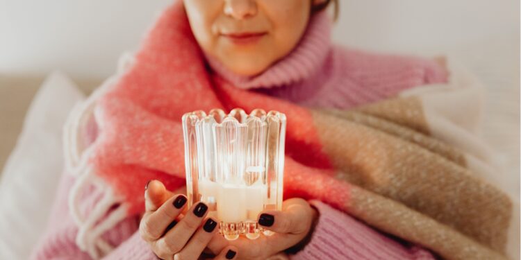 Woman enjoying winter wellness with candles in Danish hygge style interior featuring warm lighting and cozy textiles