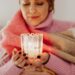 Woman enjoying winter wellness with candles in Danish hygge style interior featuring warm lighting and cozy textiles