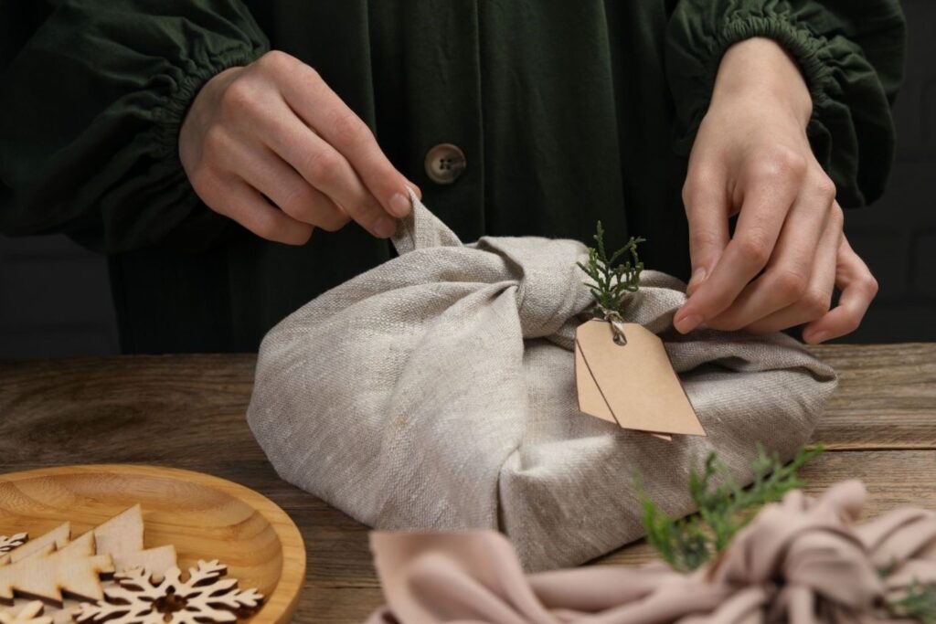 Beautiful Furoshiki fabric gift wrapping technique for zero-waste Christmas using reusable cloth and natural twine, representing sustainable European holiday traditions eliminating single-use paper waste