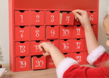 little girl in christmas outfit in front of an advent calendar