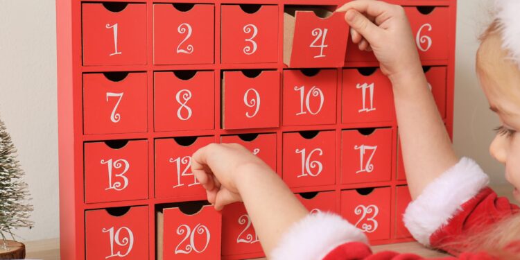 little girl in christmas outfit in front of an advent calendar