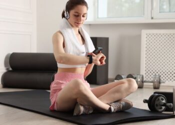 European woman checking wearable fitness tracker showing health data representing wellness trends 2026 with AI-powered personalized technology monitoring heart rate and mental fitness metrics