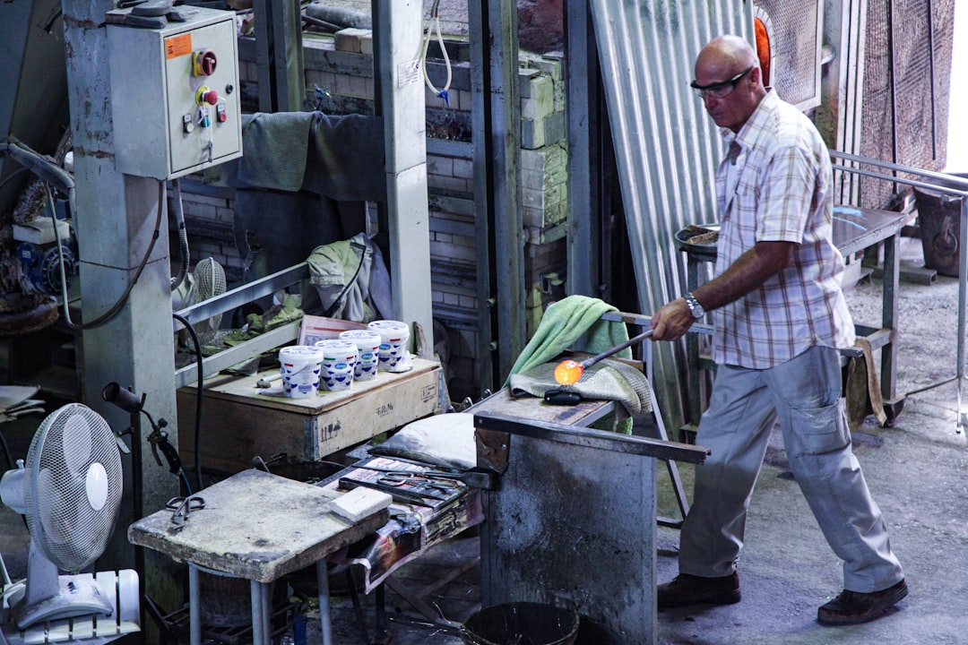 A skilled craftsman shaping molten glass in a traditional EU-protected craft regions glassblowing workshop