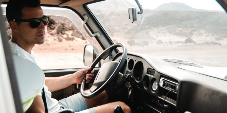 A professional van driver reviewing tachograph rules compliance data on a smart device inside a light commercial vehicle cab