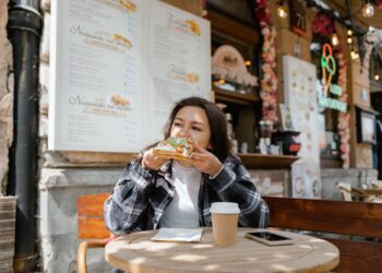 Een vrouw geniet van een maaltijd in een glutenvrije Parijse bistro en bekijkt het menu met een ontspannen uitdrukking