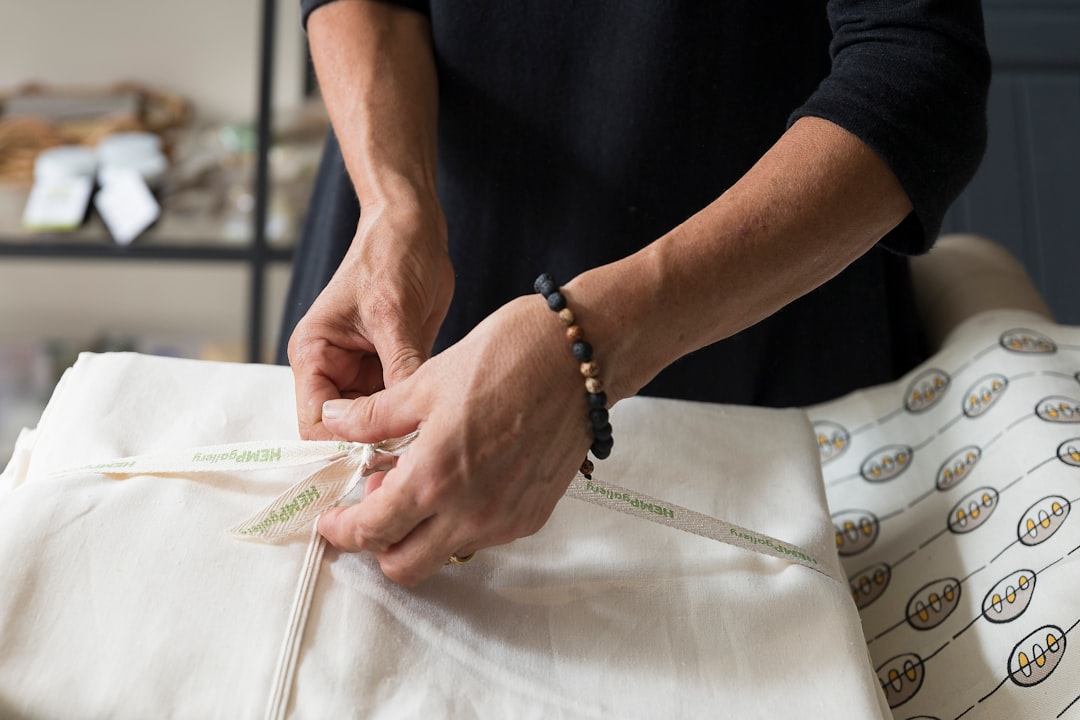 A seamstress folding linen garments in a European craft studio, representing the slow fashion values of EU linen brands