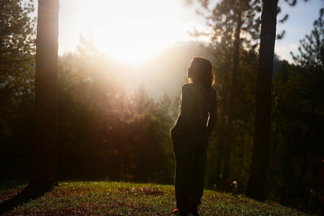 A woman walks through a sun-filled Nordic forest at sunrise, fully immersed in the restorative power of June daylight.