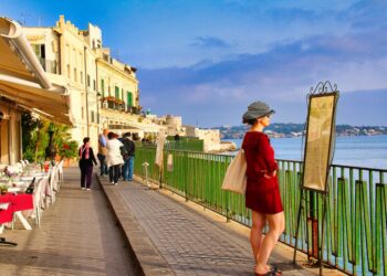 A woman strolls through a sunlit alley in one of the most charming EU beach towns in late June