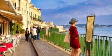 A woman strolls through a sunlit alley in one of the most charming EU beach towns in late June