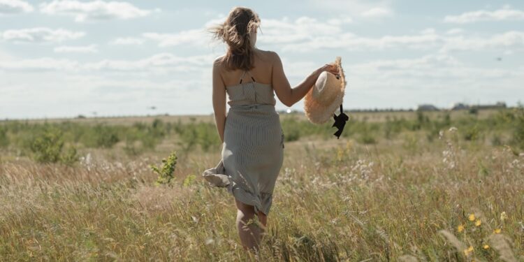 A woman wearing a flowing natural linen dress from one of Europe's leading linen brands, standing in warm summer light
