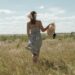 A woman wearing a flowing natural linen dress from one of Europe's leading linen brands, standing in warm summer light