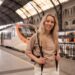 Una giovane donna che sale su un treno in Europa tenendo in mano il suo telefono con i rail pass pronti da mostrare