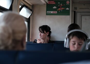 A woman reading in a private cabin aboard overnight trains across Europe, soft evening light through the window