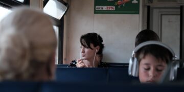 A woman reading in a private cabin aboard overnight trains across Europe, soft evening light through the window