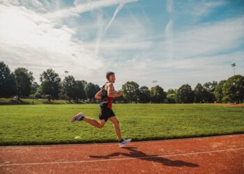 Un corredor competitivo cruza la meta en un estadio durante un evento de campeonato de atletismo europeo, celebrado por los aficionados.