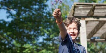 A young boy conducting a hands-on experiment at outdoor science festivals in Europe, surrounded by sunlight