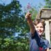 A young boy conducting a hands-on experiment at outdoor science festivals in Europe, surrounded by sunlight