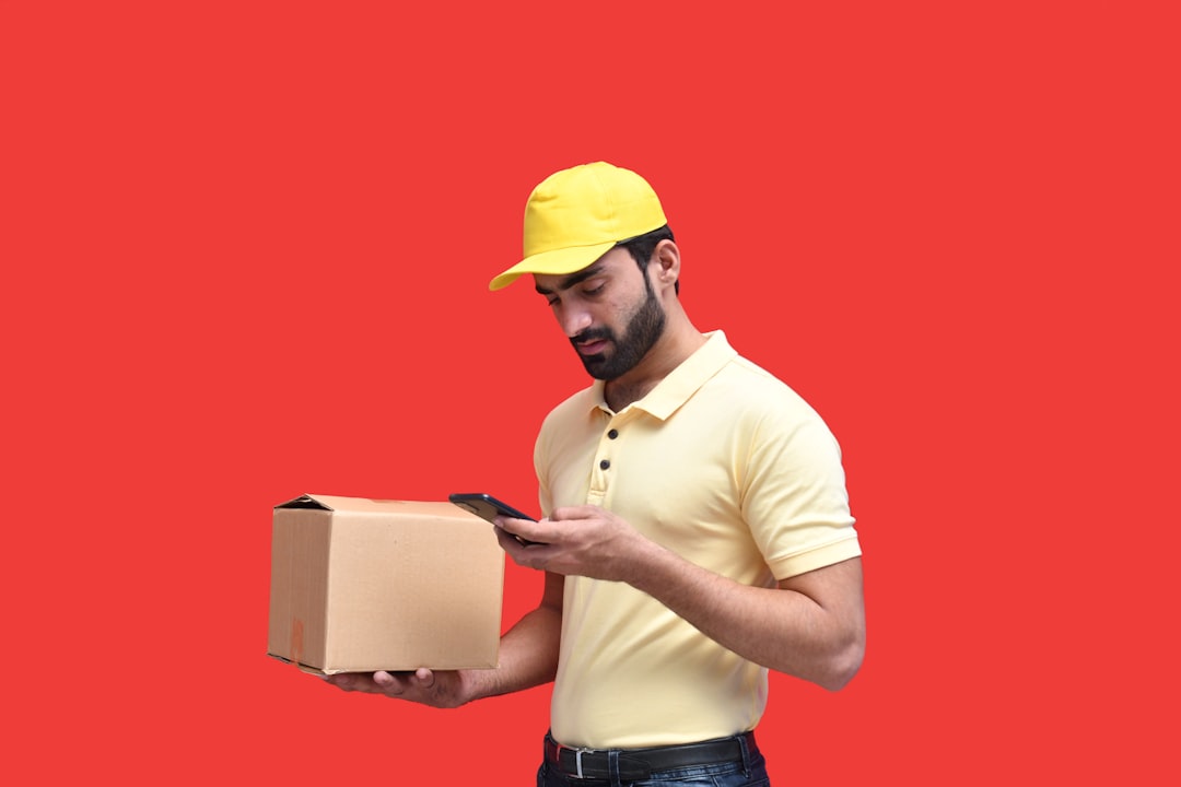 A young entrepreneur tracks a cross-border e-commerce order on his phone next to a stack of shipping parcels