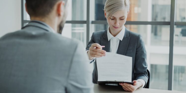 european-businesswoman-signing-trade-document-unsplash - EUwebzine A businesswoman reviews export paperwork related to the EU Mercosur trade deal at her office desk
