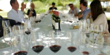 A sommelier guides a guest through a private tasting inside a historic EU vineyard cellar in Burgundy, France
