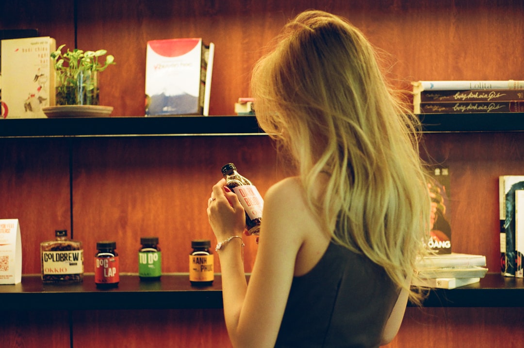 A shopper comparing two household cleaning bottles, one carrying the EU Ecolabel flower logo, on a retail shelf.
