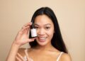 A woman carefully applying a serum containing EU skincare ingredients in a minimalist bathroom setting