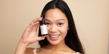 A woman carefully applying a serum containing EU skincare ingredients in a minimalist bathroom setting