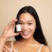 A woman carefully applying a serum containing EU skincare ingredients in a minimalist bathroom setting