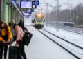 A woman boarding a European train, choosing rail travel to reduce her carbon footprint on a summer holiday