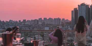 A woman enjoying dinner at one of the most elegant rooftop restaurants in Paris, with the city skyline glowing at sunset