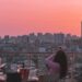 A woman enjoying dinner at one of the most elegant rooftop restaurants in Paris, with the city skyline glowing at sunset