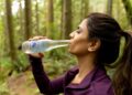 A woman drinking water outdoors in summer heat, illustrating how to stay healthy during a European heatwave