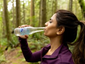 A woman drinking water outdoors in summer heat, illustrating how to stay healthy during a European heatwave