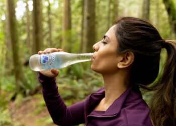 A woman drinking water outdoors in summer heat, illustrating how to stay healthy during a European heatwave