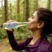 A woman drinking water outdoors in summer heat, illustrating how to stay healthy during a European heatwave