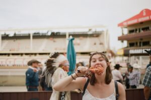 A woman carefully reading allergen free product labels at a vibrant European summer festival market stall