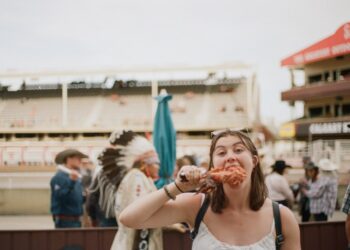 A woman carefully reading allergen free product labels at a vibrant European summer festival market stall