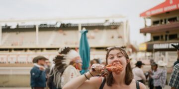 A woman carefully reading allergen free product labels at a vibrant European summer festival market stall