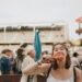 A woman carefully reading allergen free product labels at a vibrant European summer festival market stall