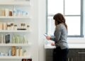 A woman carefully examines a product label in a pharmacy, reflecting the transparency promised by EU cosmetic standards.