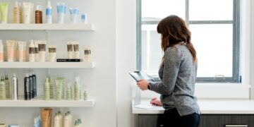 A woman carefully examines a product label in a pharmacy, reflecting the transparency promised by EU cosmetic standards.