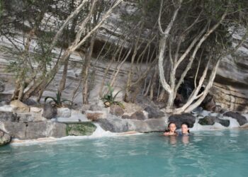 A woman relaxing in a certified thermal spa pool surrounded by historic stone architecture in Europe