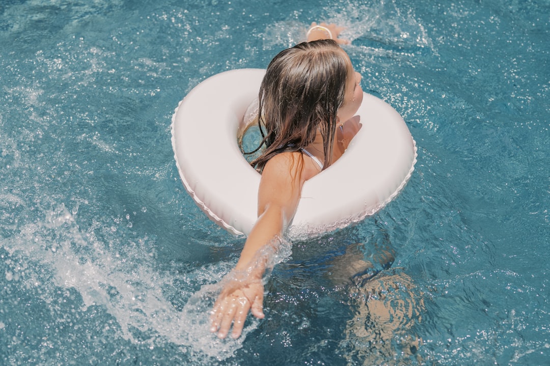 A woman relaxing in an outdoor thermal pool at a luxury EU aqua park surrounded by nature