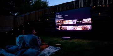 A crowd of people seated on a summer evening watching an open-air cinema screening at a European festival