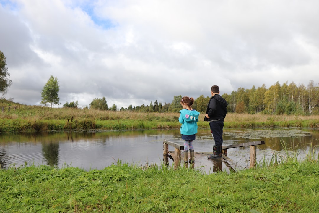 A young child looks through binoculars at a wetland nature camp, guided by an educator in a protected European reserve.